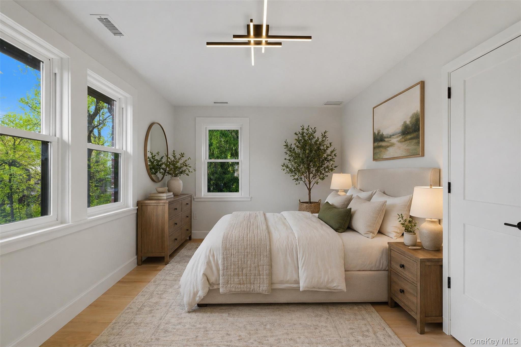 40 Calhoun Avenue New Rochelle, NY 10801 - Photo 17 of 49 Light-filled room featuring wood-finish flooring, multiple windows with white trim, a contemporary ceiling light fixture, and a solid white interior door with black hardware