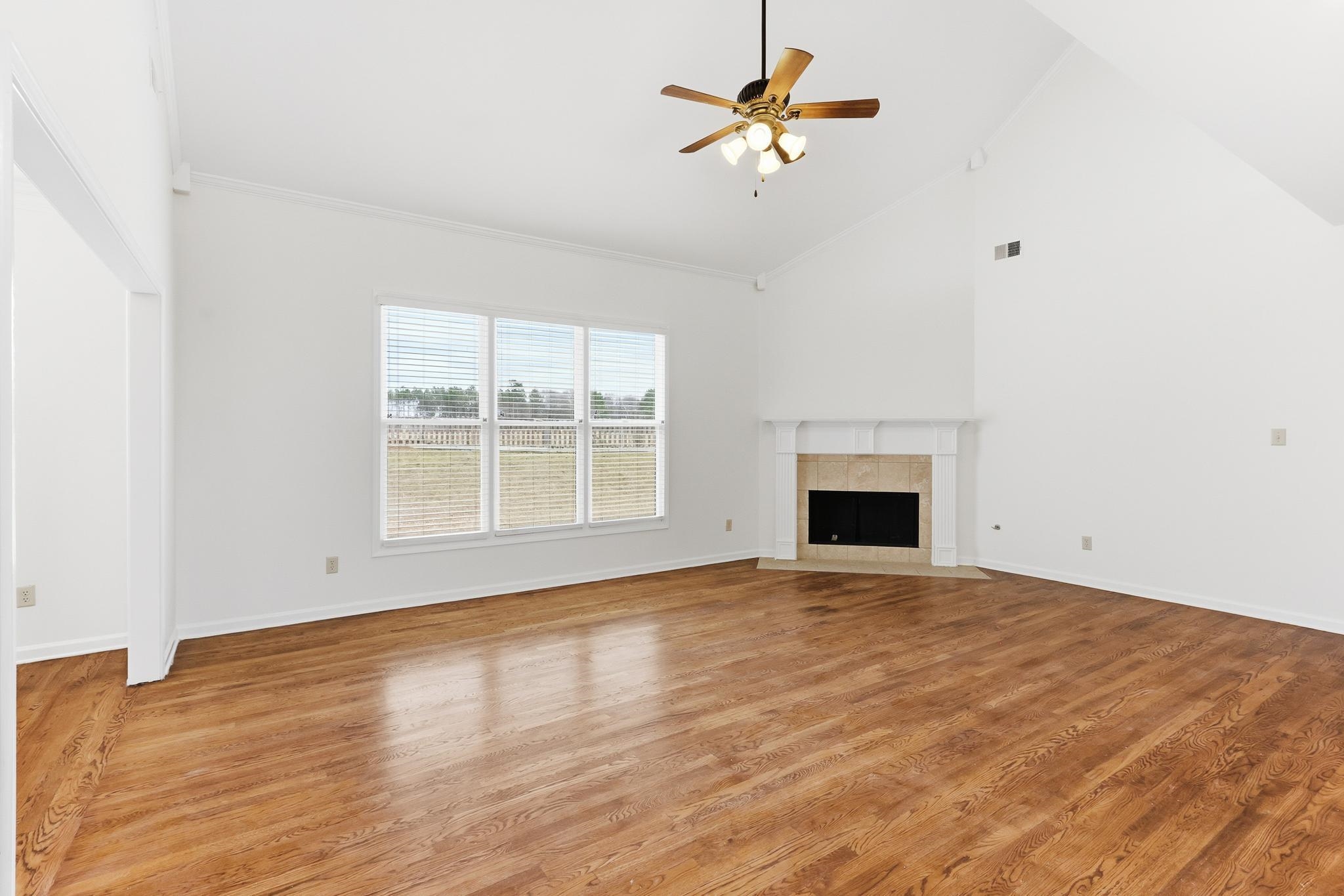 4854 Fox Springs Drive Collierville, TN 38017 - Photo 7 of 39 Unfurnished living room with ceiling fan, a tile fireplace, light wood-type flooring, and lofted ceiling