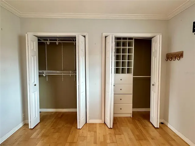 a view of an empty room with wooden floor and closet