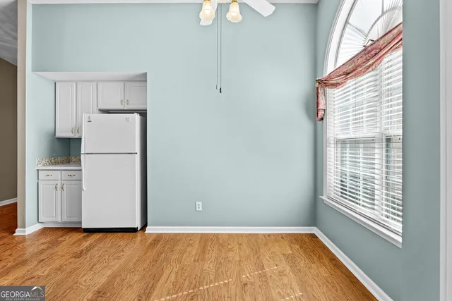 a view of a kitchen with a fridge wooden floor and a ceiling fan