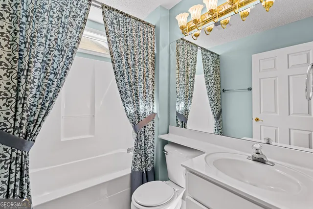 an empty room with a chandelier fan and windows