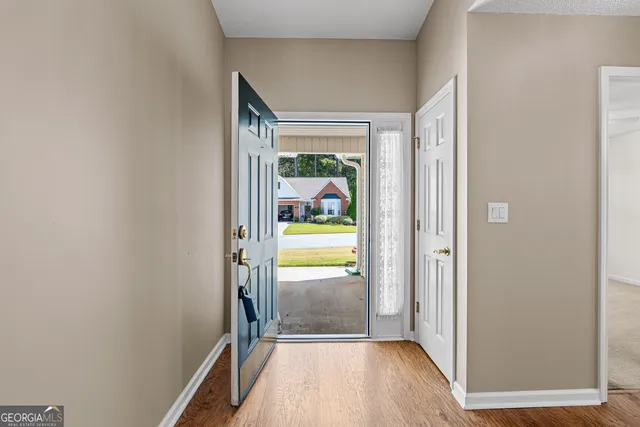 a view of a hallway with wooden floor and a room