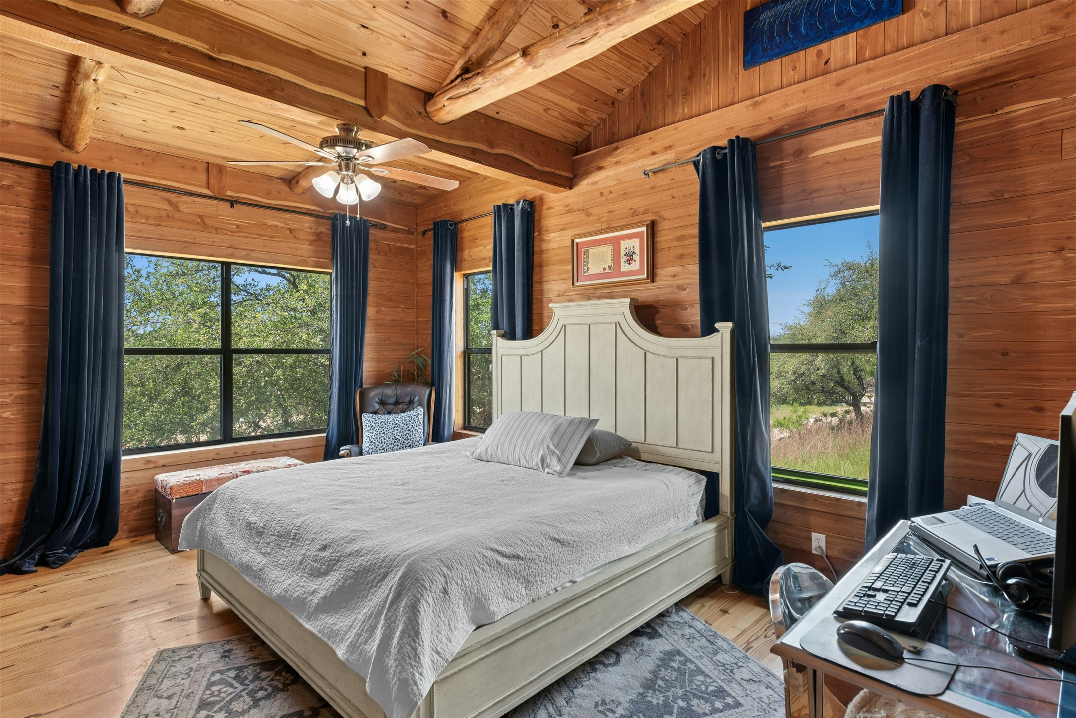 496 Middleton Road Spicewood, TX 78669 - Photo 19 of 40 Wood-paneled room featuring a sloped ceiling with exposed beams, multiple windows, and wood-finish flooring