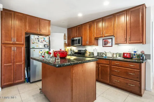 a kitchen with stainless steel appliances granite countertop a refrigerator and a stove top oven
