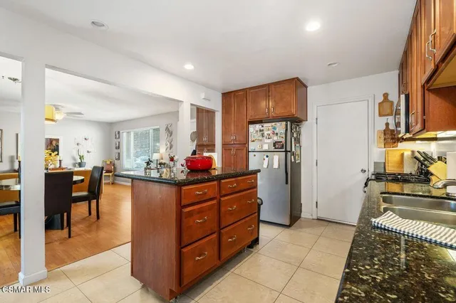 a kitchen with stainless steel appliances kitchen island granite countertop a refrigerator and cabinets
