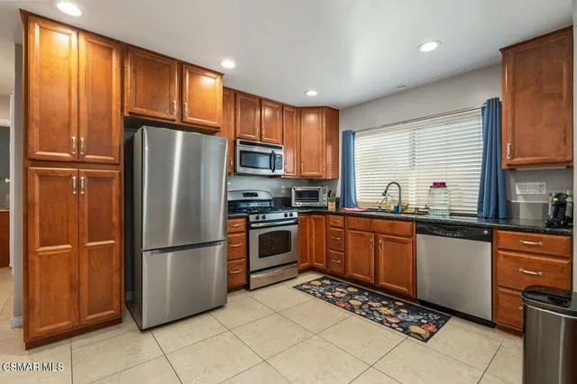 a kitchen with granite countertop stainless steel appliances a refrigerator sink and microwave