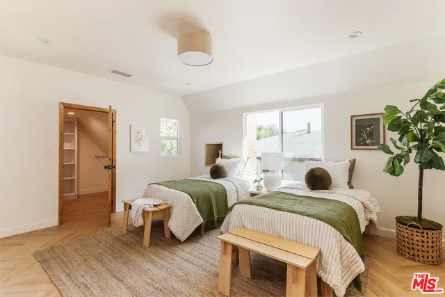 a bedroom with two beds and a potted plant