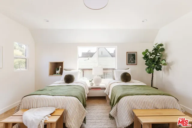 a bedroom with two beds and a potted plant