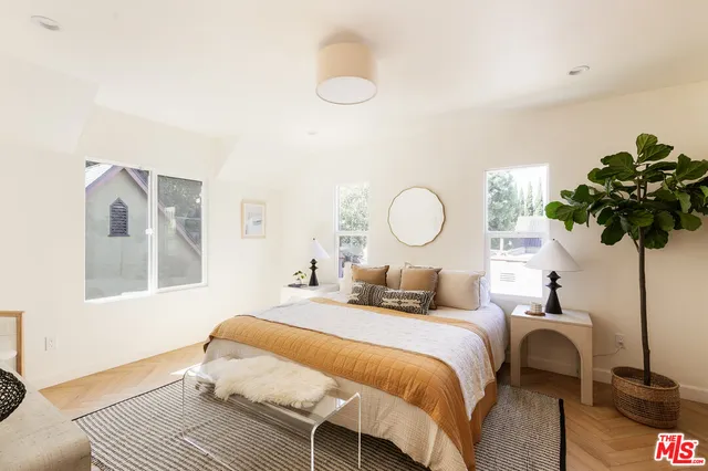 a bedroom with a bed flowerpot and wooden floor