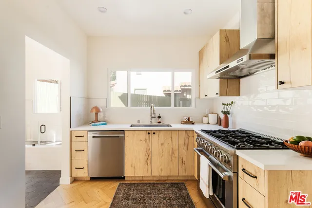 a kitchen with stainless steel appliances a sink a stove and a window