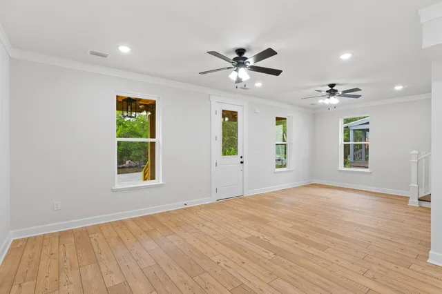a view of an empty room with a window and wooden floor