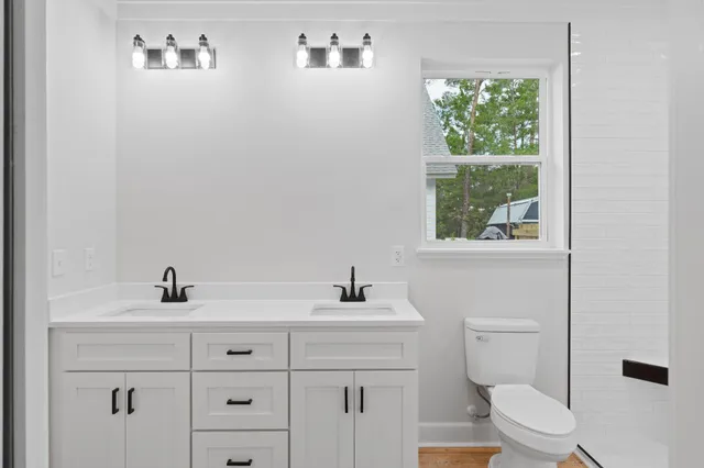 a bathroom with a toilet a sink a window and mirror