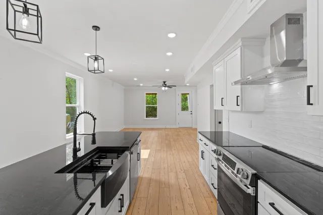 a kitchen with stainless steel appliances granite countertop a stove a sink a refrigerator and a wooden floors