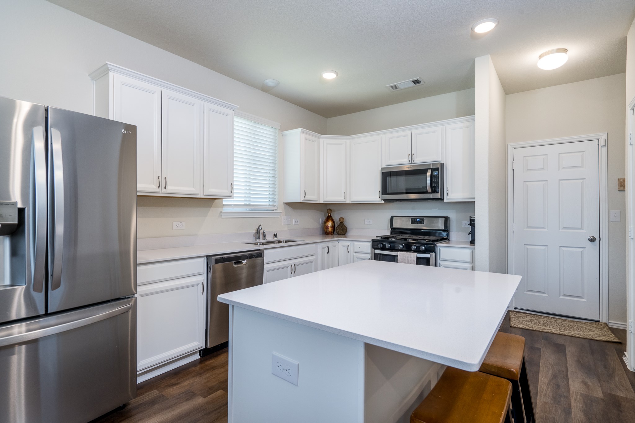 4256 Pine Still Road Conroe, TX 77304 - Photo 7 of 21 a kitchen with a sink a microwave a refrigerator and cabinets