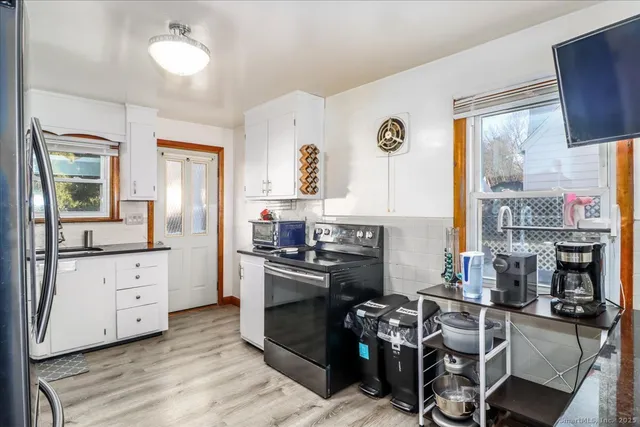 a kitchen with stainless steel appliances granite countertop a stove top oven a sink a dining table and chairs with wooden floor