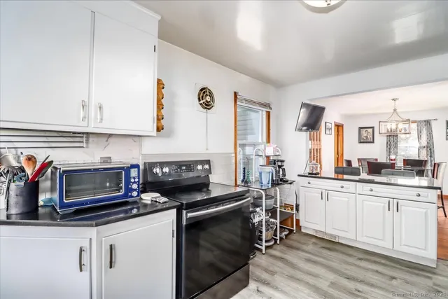 a kitchen with stainless steel appliances granite countertop a stove a sink and white cabinets