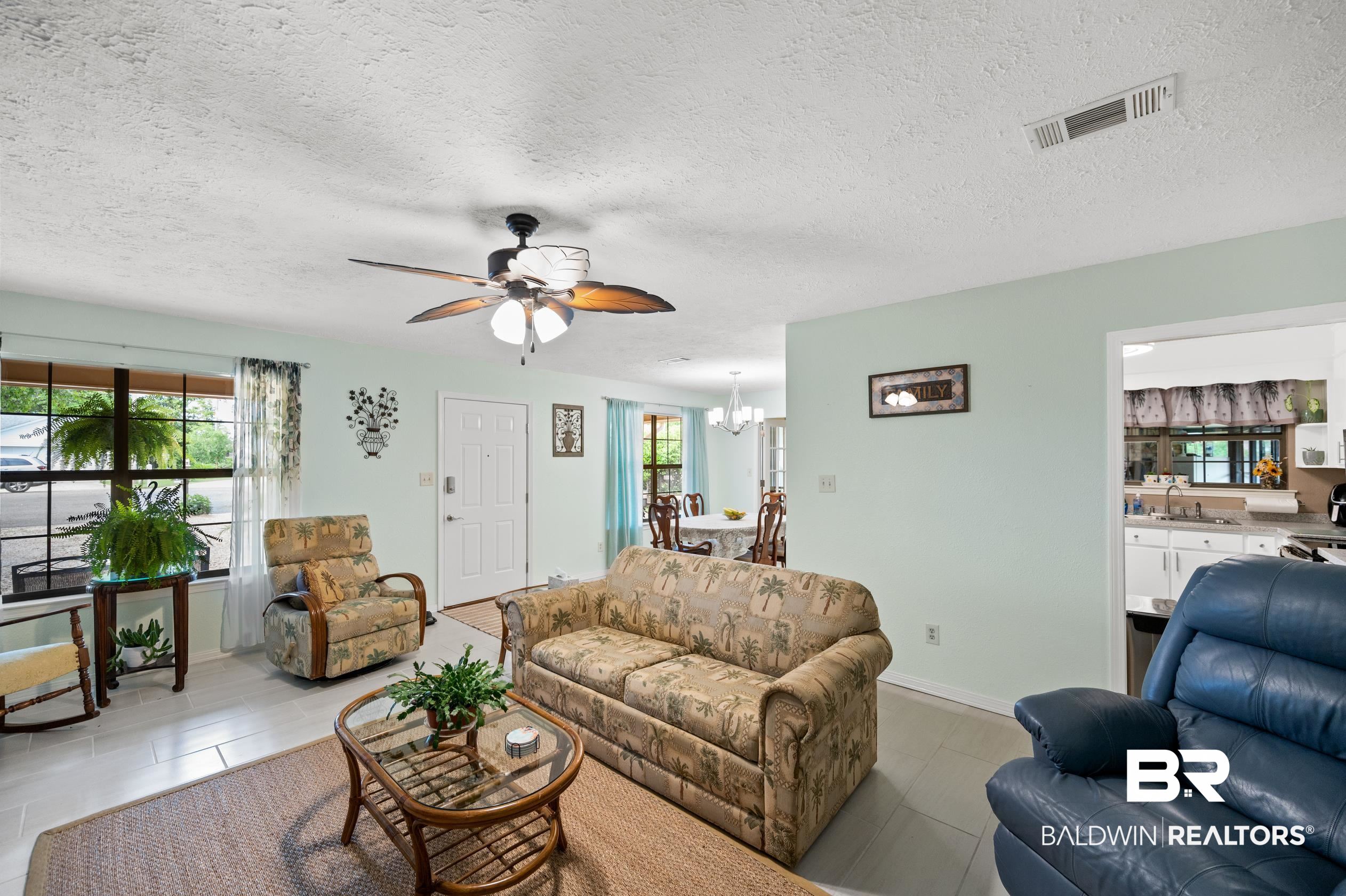 2772 Santa Rosa Circle Lillian, AL 36549 - Photo 7 of 50 Tiled living room featuring ceiling fan with notable chandelier, sink, and a textured ceiling