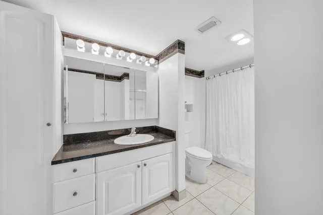 a bathroom with a granite countertop sink a toilet a mirror and shower
