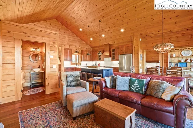 a kitchen with stainless steel appliances granite countertop a stove a refrigerator a sink a dining table and chairs with wooden floor