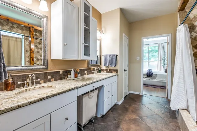 a en suite bathroom with a granite countertop sink and a mirror