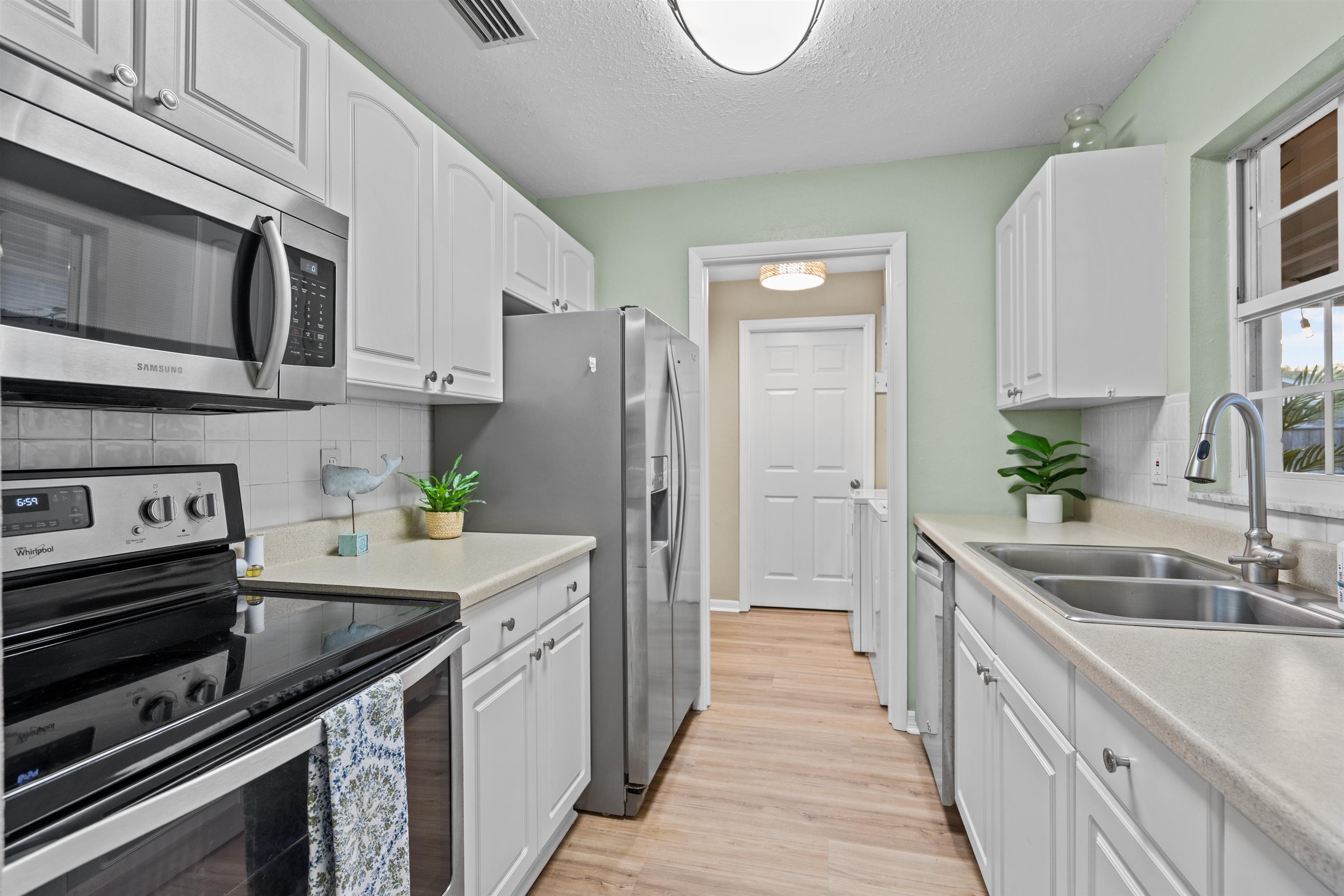 285 Trillo Street St. Augustine, FL 32086 - Photo 17 of 48 Kitchen with stainless steel appliances, backsplash, white cabinets, a textured ceiling, and light countertops