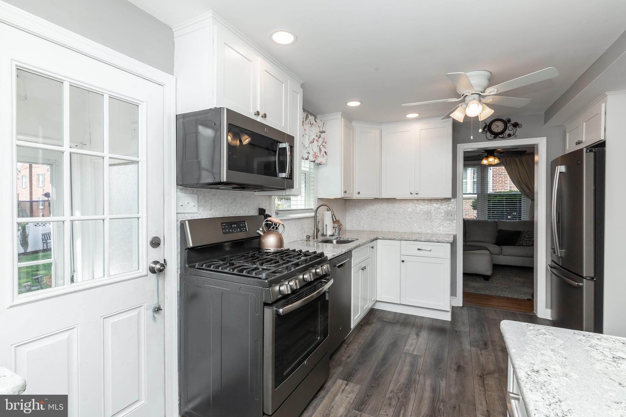 148 Signal Road Drexel Hill, PA 19026 - Photo 7 of 37 a kitchen with granite countertop a stove top oven a sink dishwasher a refrigerator and a dining table with wooden floor