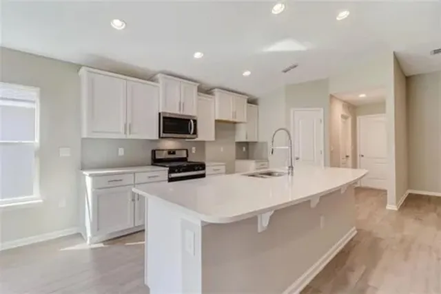 a kitchen with a sink a stove a microwave and white cabinets