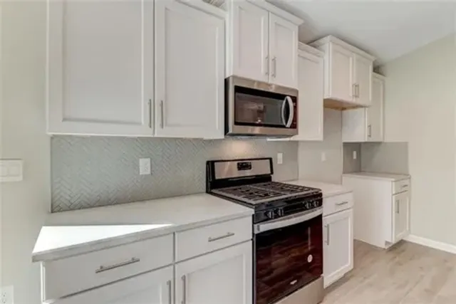 a kitchen with white cabinets stainless steel appliances and a sink