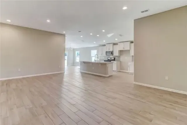 a view of kitchen with kitchen island wooden floor center island and stainless steel appliances