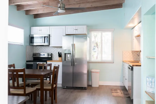 a kitchen with stainless steel appliances granite countertop a refrigerator a stove a sink dishwasher and a dining table with wooden floor