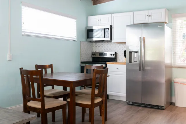 a kitchen with stainless steel appliances a table chairs microwave and refrigerator