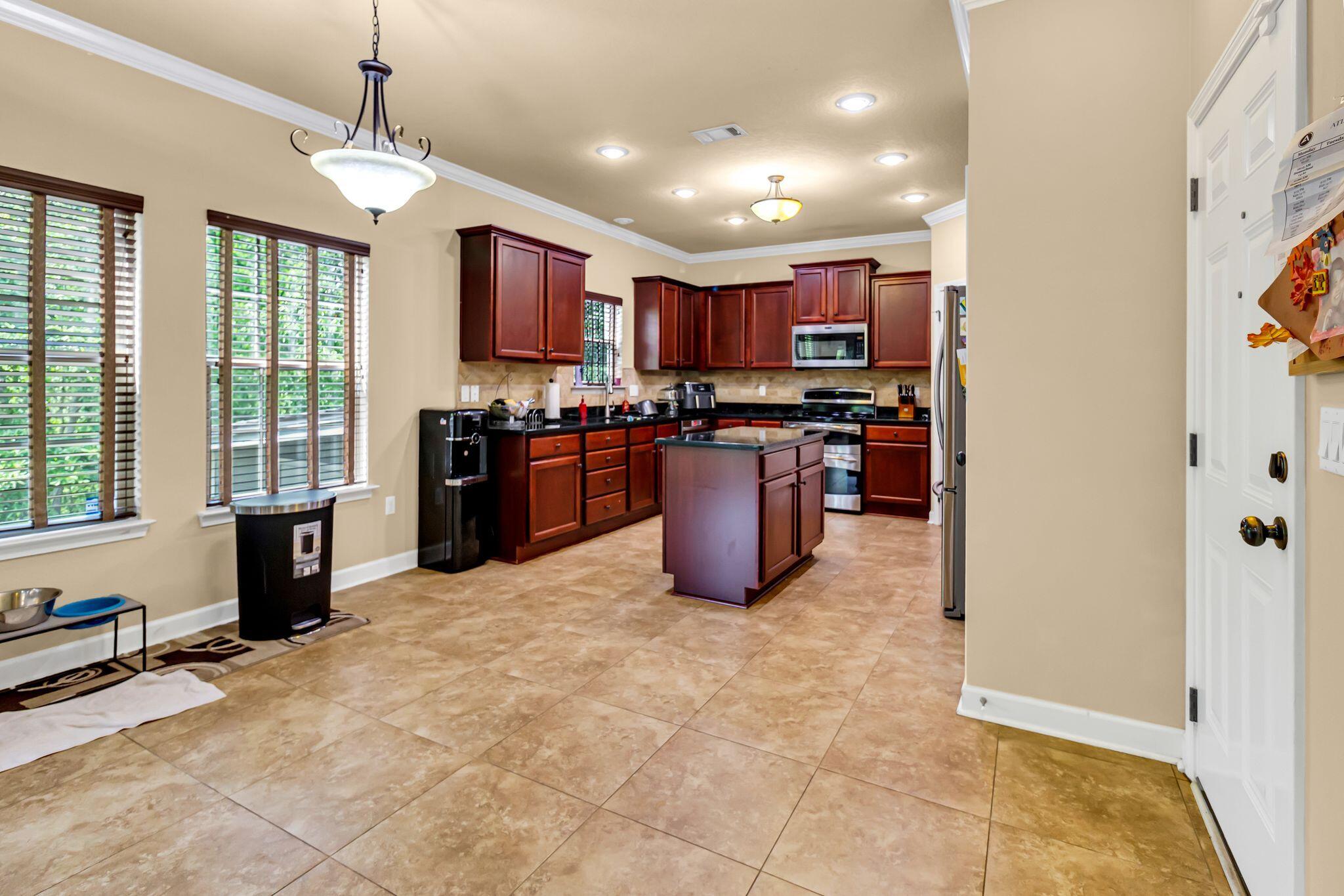 4558 Hermosa Road Crestview, FL 32539 - Photo 9 of 50 a kitchen with stainless steel appliances granite countertop a stove top oven a sink dishwasher a dining table and chairs with wooden floor