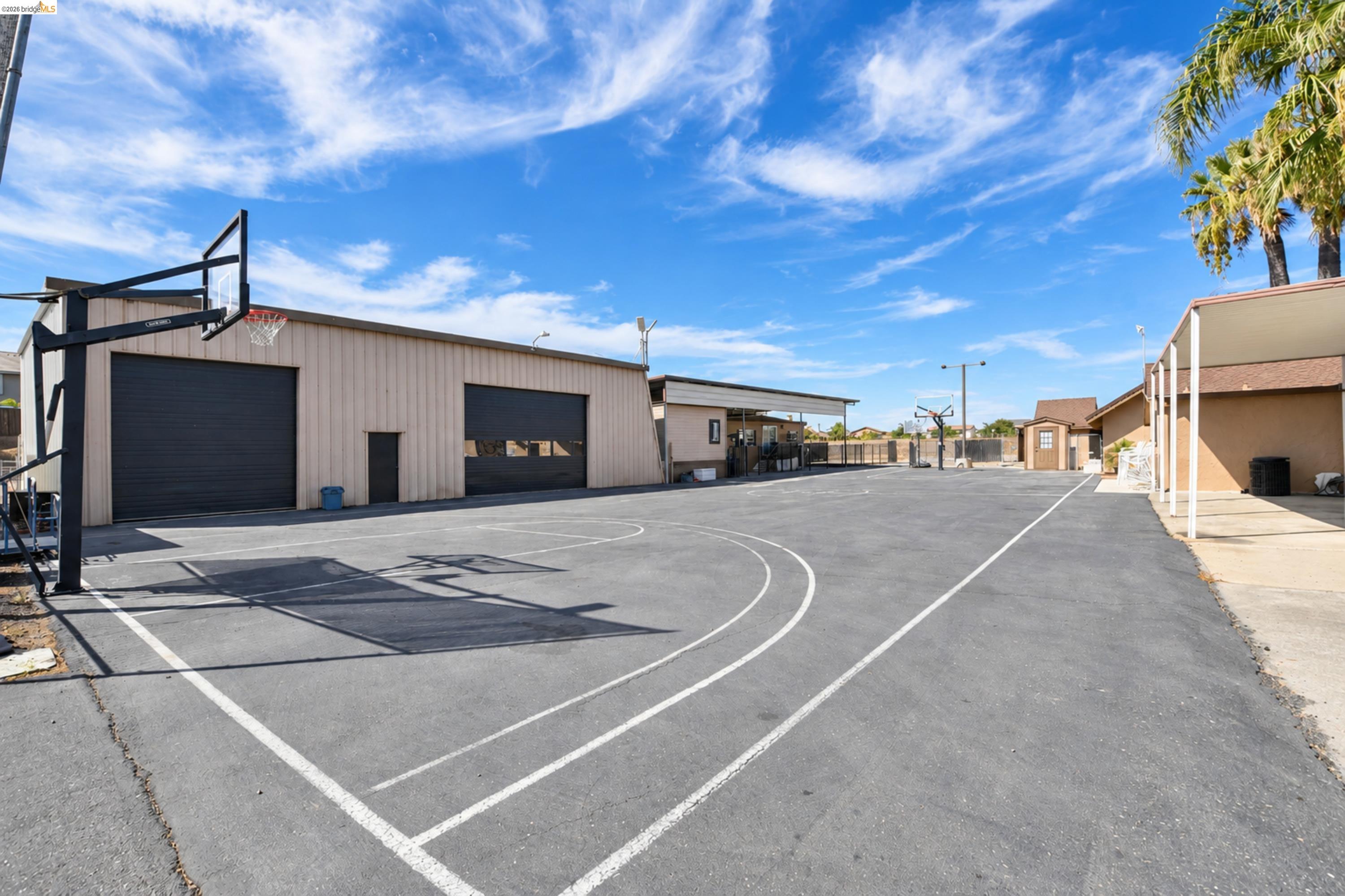 340 West Bolton Road Oakley, CA 94561 - Photo 73 of 87 Paved court with painted markings, basketball hoop, and a large metal-sided building with two roll-up doors