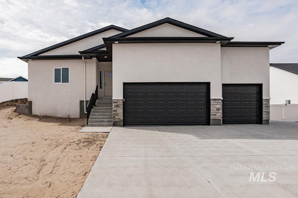 View of front of house featuring stucco siding, stone siding, a garage, and concrete driveway