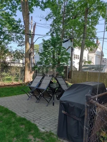 a view of a backyard with table and chairs with wooden fence and plants