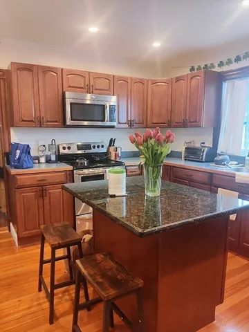 a kitchen with stainless steel appliances granite countertop a table chairs sink and cabinets