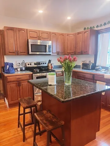 a kitchen with stainless steel appliances granite countertop a table chairs sink and cabinets