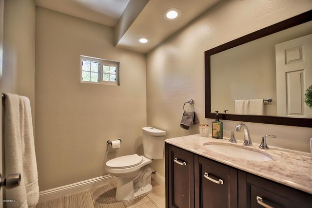 a bathroom with a granite countertop toilet a sink and a mirror