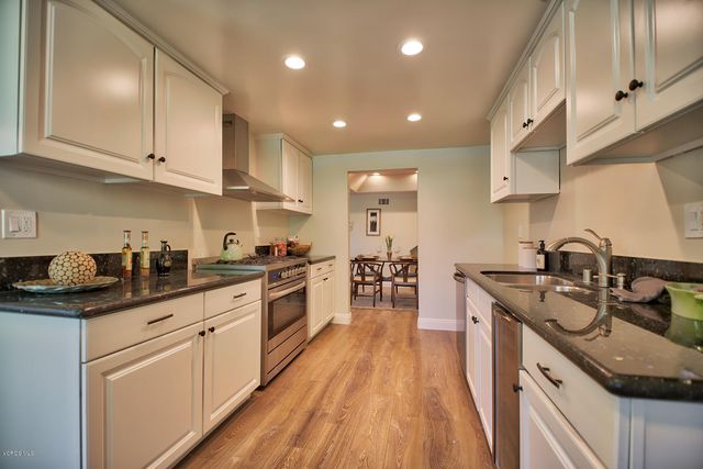a kitchen with stainless steel appliances granite countertop sink stove top oven and cabinets