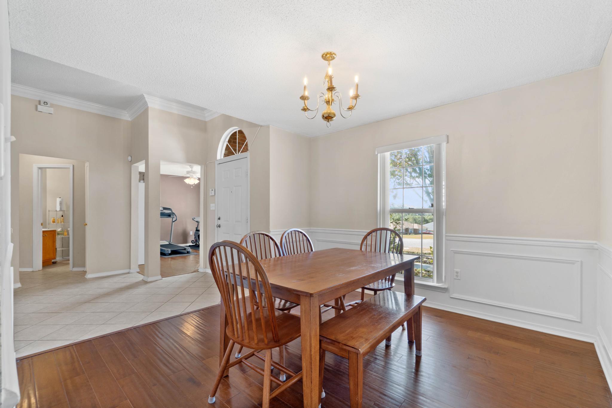 664 Brunson Street Crestview, FL 32536 - Photo 11 of 49 a dining room with furniture wooden floor a rug and a chandelier