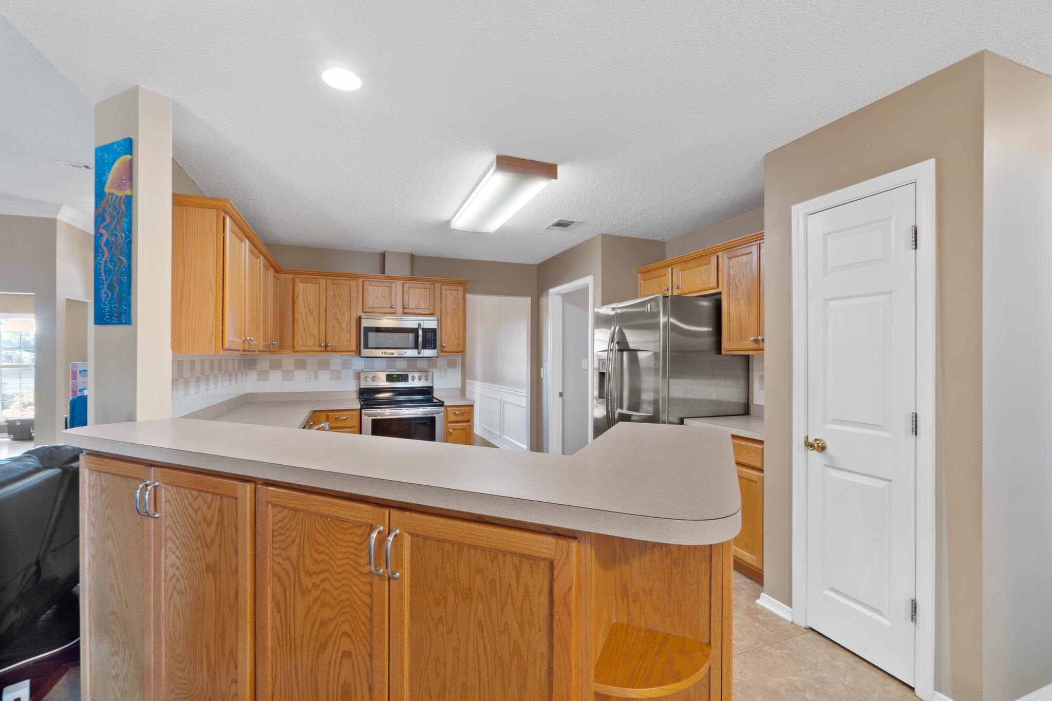 664 Brunson Street Crestview, FL 32536 - Photo 23 of 49 a kitchen with stainless steel appliances granite countertop a sink a stove and a refrigerator