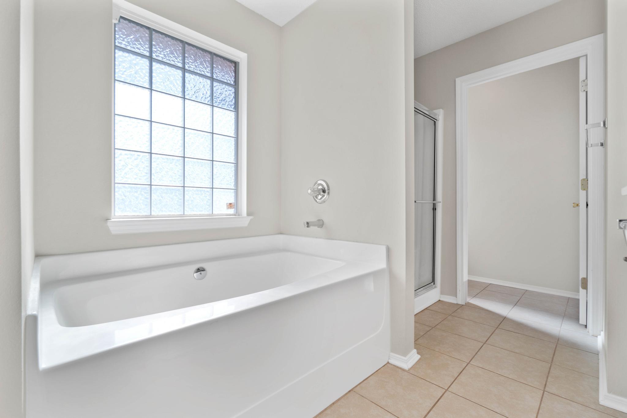 664 Brunson Street Crestview, FL 32536 - Photo 27 of 49 a spacious bathroom with a bathtub and window