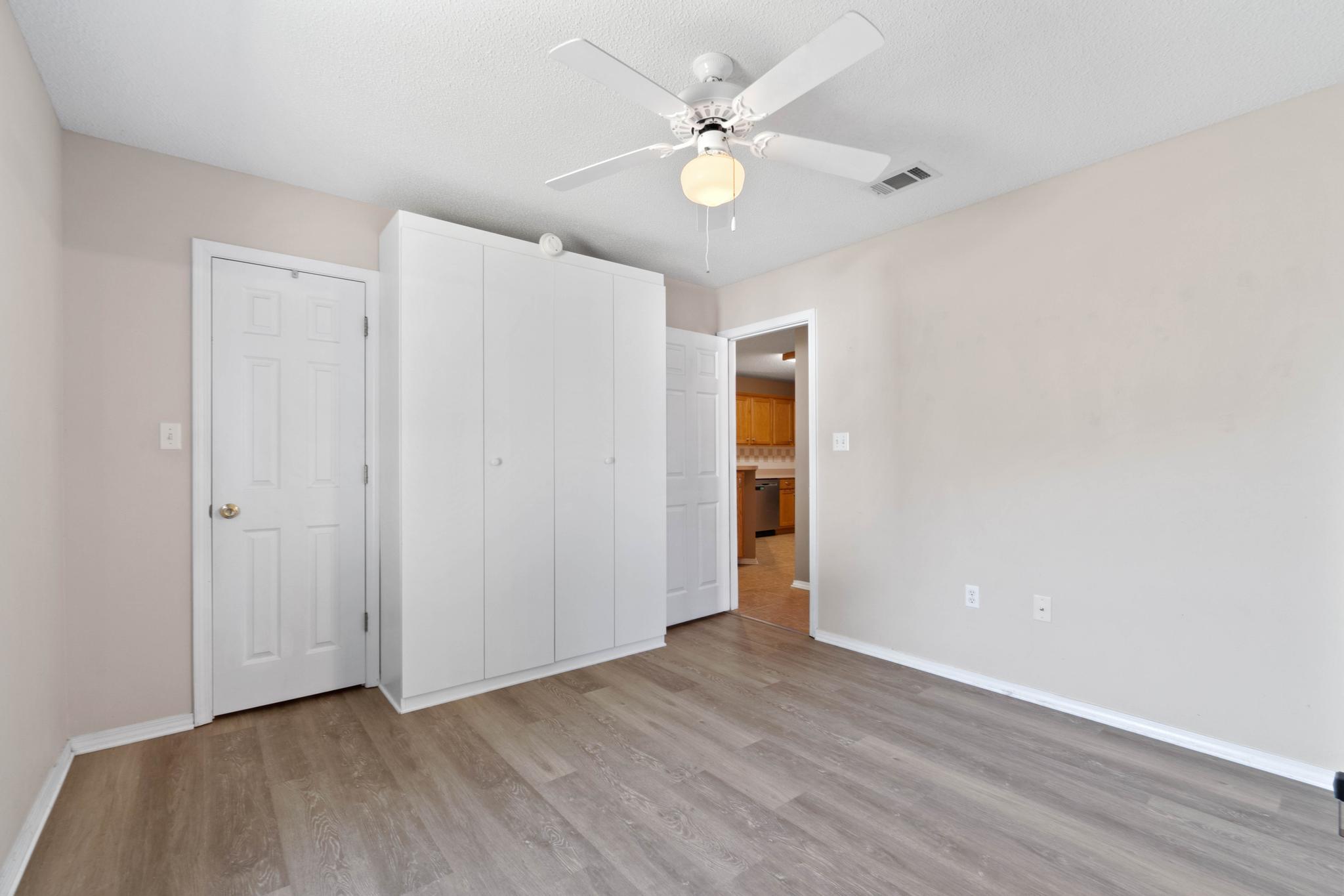 664 Brunson Street Crestview, FL 32536 - Photo 39 of 49 an empty room with wooden floor and ceiling fan