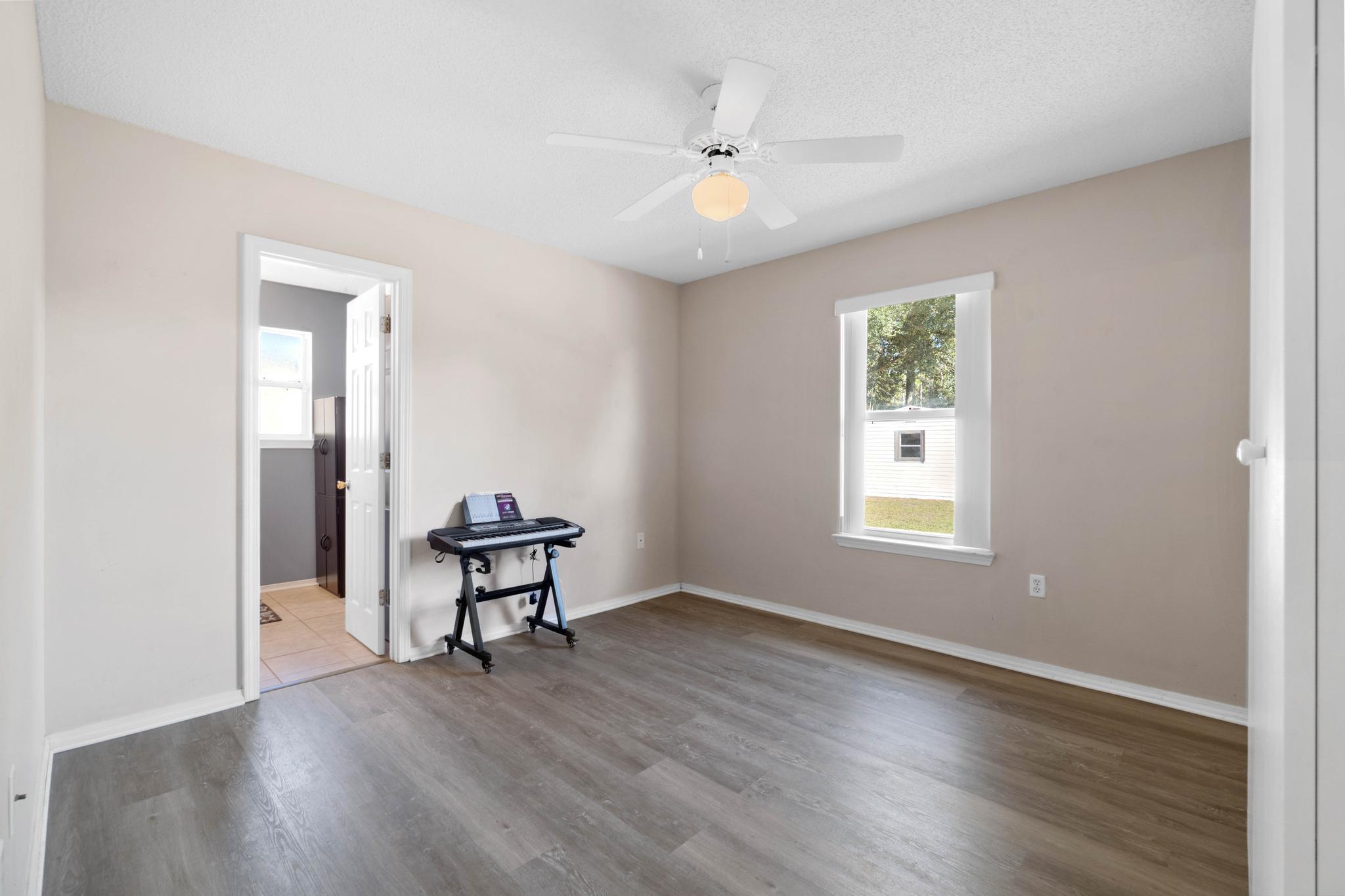 664 Brunson Street Crestview, FL 32536 - Photo 40 of 49 an empty room with windows and a chandelier fan