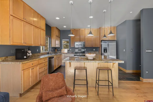 a kitchen with stainless steel appliances granite countertop a sink a stove a refrigerator and cabinets