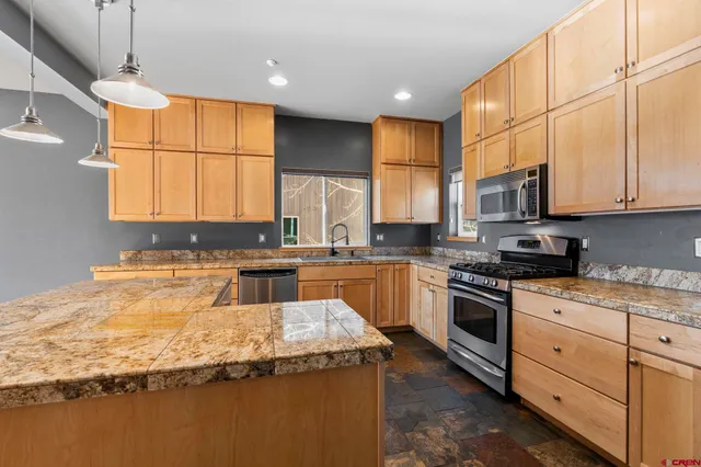 a kitchen with granite countertop a sink a counter space appliances and cabinets