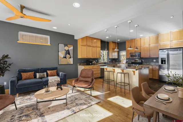a living room with stainless steel appliances furniture a rug and a kitchen view