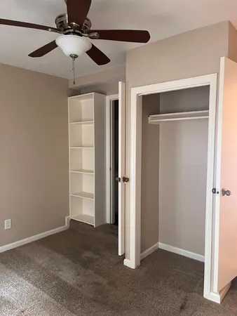 an empty room with closet and a ceiling fan