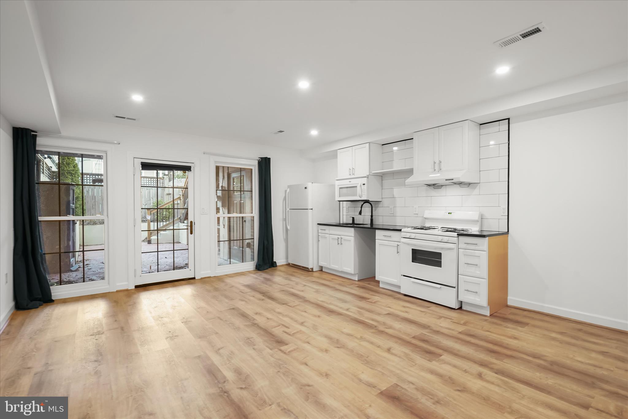 3626 T Street Northwest Washington, DC 20007 - Photo 38 of 61 a large white kitchen with granite countertop a stove top oven a sink dishwasher and white cabinets with wooden floor