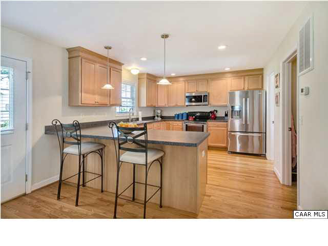 128 Roy's Place Charlottesville, VA 22902 - Photo 4 of 16 a kitchen with stainless steel appliances kitchen island granite countertop a table chairs and a refrigerator